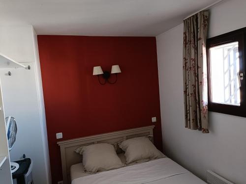 une chambre avec un mur rouge et un lit avec deux oreillers dans l'établissement Magnifique bord de mer 3 chambres, au Cap d'Agde