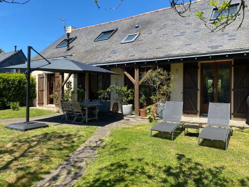 une maison avec une table, des chaises et un parasol dans l'établissement Chambres d’hôtes au calme, proche de la mer, à Saint-Nazaire