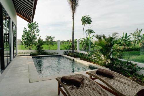 a swimming pool in the middle of a patio with two chairs at Villa Alaya No 4 in Cemagi