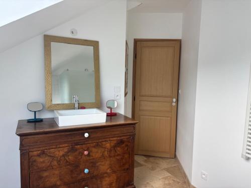 La salle de bains est pourvue d'un lavabo et d'un miroir sur une commode. dans l'établissement Maison de Campagne, à Saint-Mars-dʼOutillé