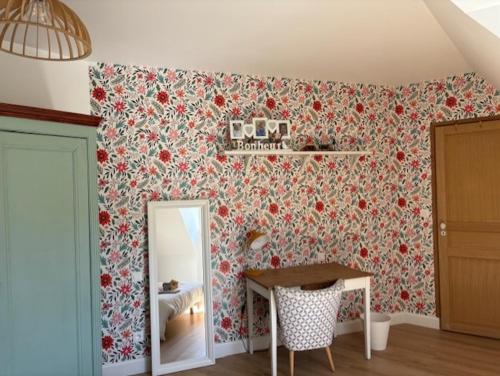 une chambre avec un papier peint fleuri et un miroir dans l'établissement Maison de Campagne, à Saint-Mars-dʼOutillé