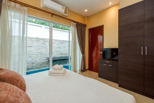 a bedroom with a bed and a large window at The Ville Jomtien- 3 Bedrooms Deluxe Pool Villa in Jomtien Beach