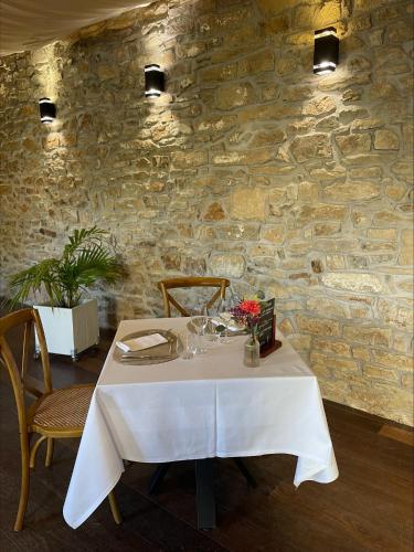 a dining room with a white table and a stone wall at Manoir de Kerhuel de Quimper in Plonéour-Lanvern