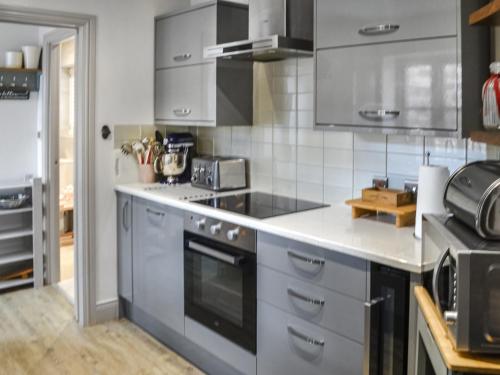 a kitchen with stainless steel appliances and gray cabinets at The Old Telephone Exchange in Rothbury