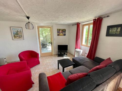 a living room with a couch and red chairs at Charming little house with garden, stunning view in Fayence