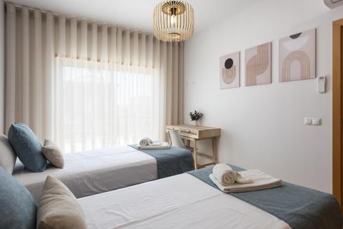a bedroom with two beds and a table and a chandelier at Villa da Ria - by HD Properties in Monte Negro