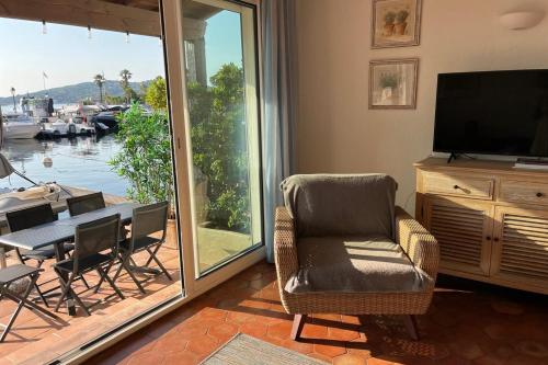 un salon avec une télévision et une table avec des chaises dans l'établissement La Terrasse de Port Grimaud - Welkeys, à Grimaud