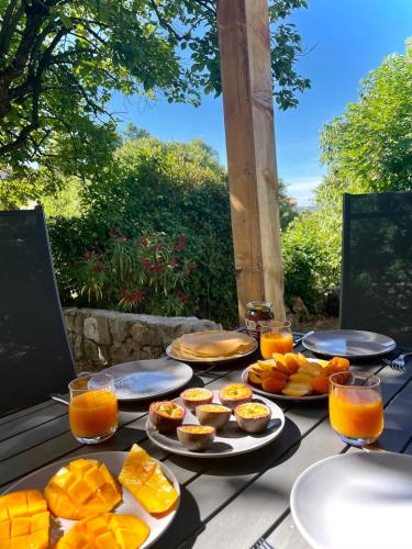 une table garnie d'assiettes de nourriture et de jus d'orange dans l'établissement Charming little house with garden, stunning view, à Fayence
