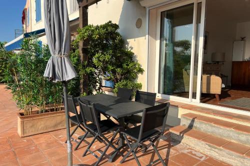 une table et des chaises avec un parasol sur une terrasse dans l'établissement La Terrasse de Port Grimaud - Welkeys, à Grimaud