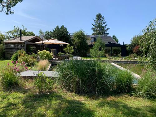 a garden with a house with an umbrella and a pond at Maison de ARCHITECTE in Préaux