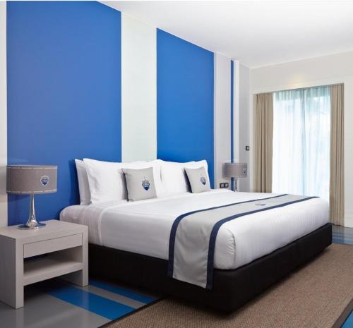 a bedroom with a large bed with a blue wall at Amari Buriram United in Buriram