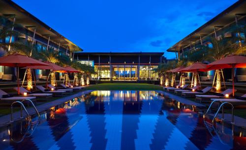 a pool with chairs and umbrellas in front of a building at Amari Buriram United in Buriram