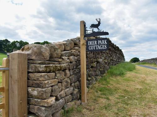 a sign on a stone wall next to a fence at Deer Park - Uk33360 in Reeth