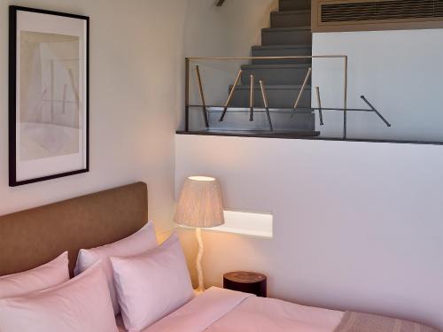 a bedroom with a bed with pink pillows and a staircase at Grecotel Astir Palace in Alexandroupoli