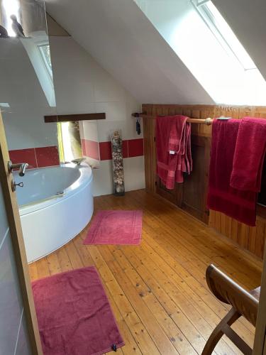 une salle de bain mansardée avec une baignoire et des serviettes rouges dans l'établissement La Chambre du Manoir, à La Roche-Derrien