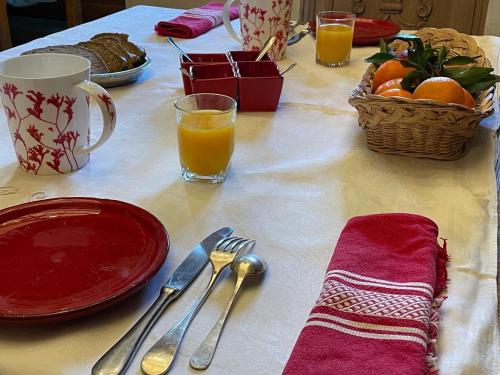 une table avec des assiettes et des ustensiles et un panier d'oranges dans l'établissement La Chambre du Manoir, à La Roche-Derrien