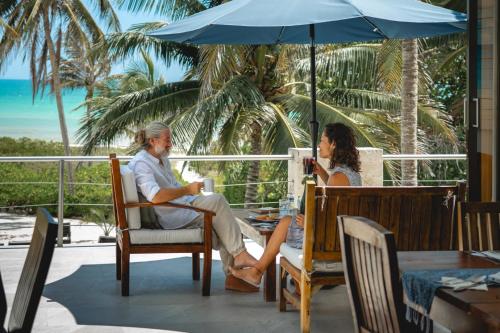 a man and woman sitting under an umbrella on a patio at Hotel La Casa Cielo solo adultos in El Cuyo
