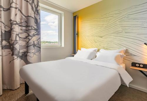 a bedroom with a large bed and a window at B&B HOTEL Mulhouse Bâle Aéroport in Hésingue