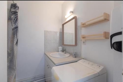 une salle de bain blanche avec un lavabo et un miroir dans l'établissement jardin plein sud, vue montagne, proche Luz Saint Sauveur, à Luz-Saint-Sauveur