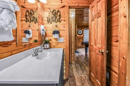 a bathroom with a white sink and wooden walls at Grand Mountain View Lodge By Ghosal Luxury Lodging in Sevierville