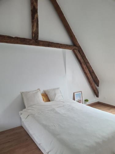 un lit blanc dans une chambre blanche avec des poutres en bois dans l'établissement Ferme Côte Opale, plage 6 min, à Tardinghen