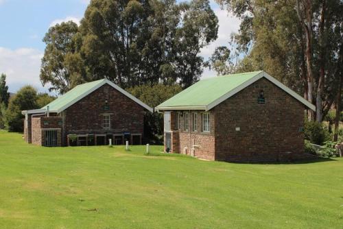 a brick building with a green roof on a field at Rivier-Plesier Cottage at Riggton River Farm in Bonnievale