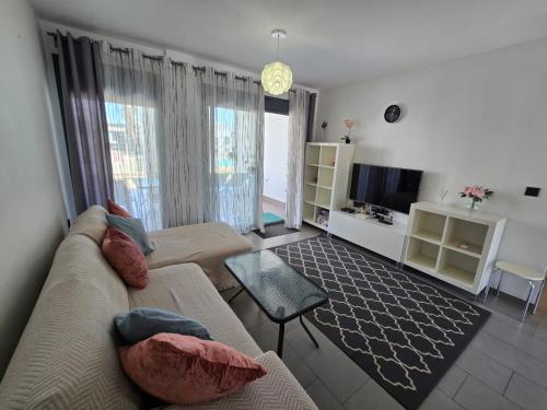 een woonkamer met een bank en een tv bij Sunny Ground floor bungalow opposite the swimming pool in Orihuela