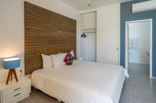 a bedroom with a white bed and a wooden headboard at Hotel La Casa Cielo solo adultos in El Cuyo