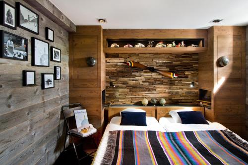 two beds in a room with wooden walls at Les Rhodos in La Clusaz