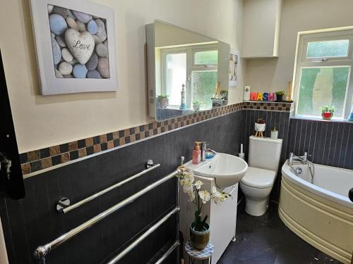 a bathroom with a sink and a toilet and a bath tub at Stunning 4 bed house with huge garden and parking in Cheam
