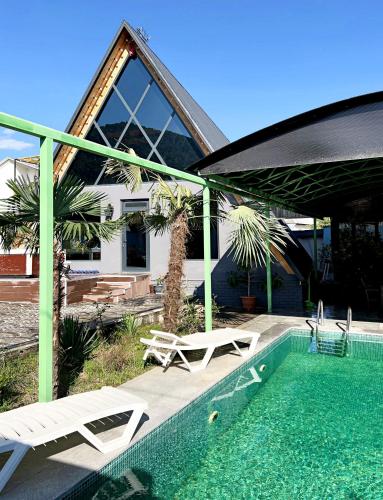 a pool with two chairs and a table and a house at NatureNest A-Frame Cabin in Gabala