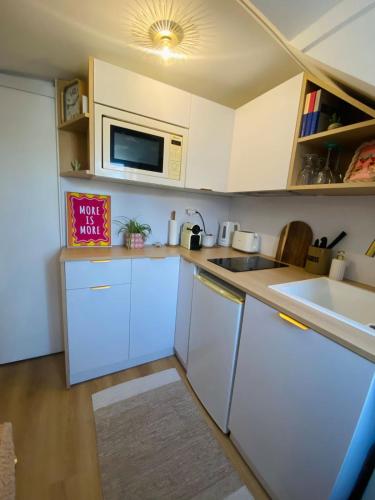 une cuisine avec des armoires blanches, un évier et un micro-ondes dans l'établissement Cozy Studio - Paris Galeries Lafayette, à Paris