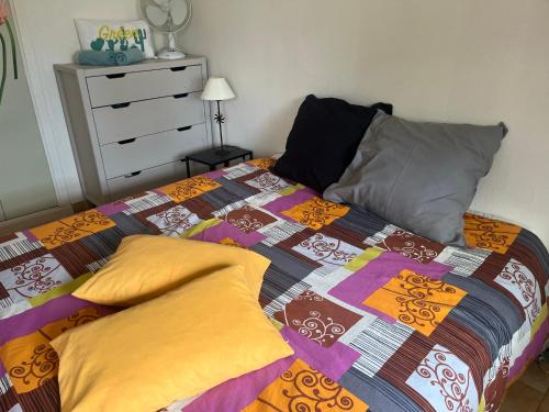 - un lit avec une couette et des oreillers colorés dans l'établissement F1 véranda jardinet en résidence front de mer, à Bernières-sur-Mer