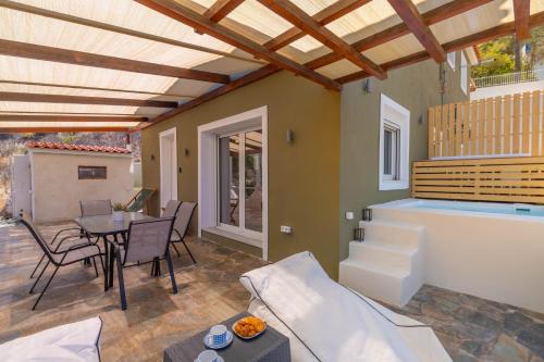 a patio with a table and chairs and a pool at Amelin Villa Paradise in Aegenitissa
