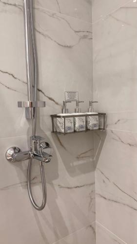 a shower in a bathroom with white marble walls at MK Luxury Serviced Apartments # 4 in Chişinău