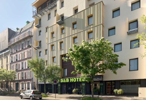 a large white building with a car parked in front of it at B&B HOTEL Paris Porte d'Orléans in Montrouge