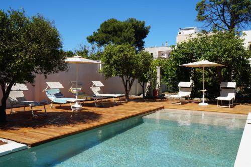 a swimming pool with chairs and umbrellas next to at Suite Royale Palazzo Villani Lubelli in Cannole
