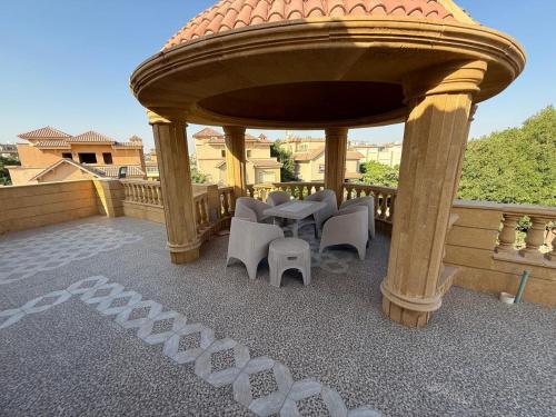 einen Pavillon mit einem Tisch und Stühlen auf dem Balkon in der Unterkunft فيلا فندقيه مع حمام سباحه وحديقه 0306-888-0106 in Kairo