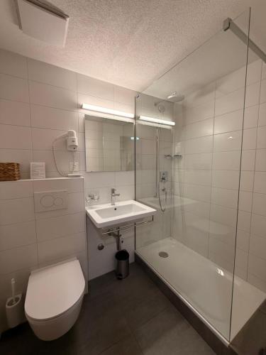 a bathroom with a toilet and a sink and a tub at Hotel Corona in Vicosoprano