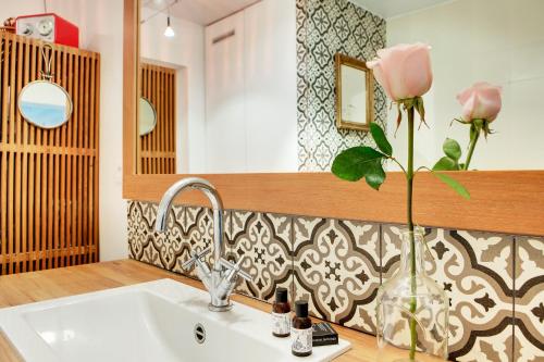 La salle de bains est pourvue d'un lavabo et d'un vase avec une rose. dans l'établissement Paris Bastille Rollin residence, à Paris
