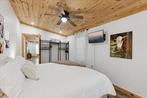 a bedroom with a white bed and a ceiling fan at Creekside Retreat Arcade Fire Pit in Pigeon Forge
