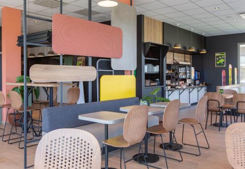 un restaurant avec des tables, des chaises et un comptoir dans l'établissement B&B HOTEL Orléans Saran, à Saran