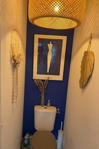 une salle de bain avec un mur bleu avec des toilettes et un tableau dans l'établissement Maison climatisée avec piscine dans le Golfe de St Tropez, à La Môle