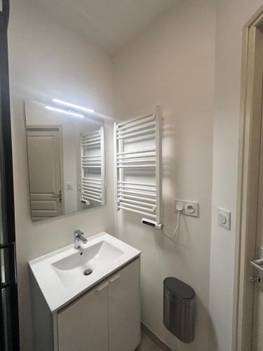 une salle de bain blanche avec un lavabo et un miroir dans l'établissement La chambre de Bouloc confortable et calme, à Bouloc