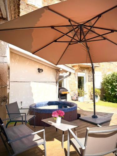 une terrasse avec un parasol et un bain à remous dans l'établissement Le Gîte d'Antoine - Beaujolais, à Saint-Étienne-des-Oullières