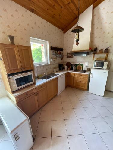 - une grande cuisine avec des placards en bois et des appareils blancs dans l'établissement Maison bord rivière avec accès ponton Beaumont sur sarthe, à Beaumont-sur-Sarthe