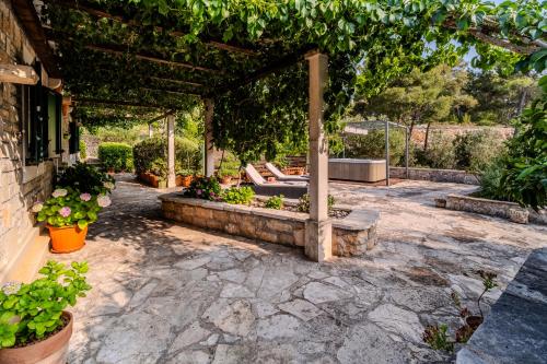 a patio with a pergola with a bench and plants at Holiday Home Sarbunara in Milna