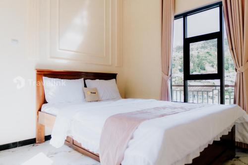 a bedroom with a white bed with a window at Kurniawan By Travelink in Dieng