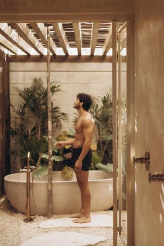 a man standing in front of a bath tub at NABOA Hotel Tulum in Tulum
