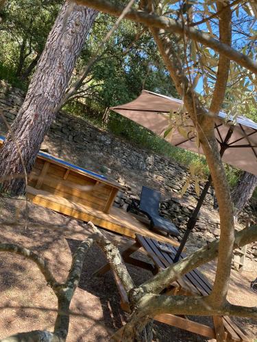 a picnic table with an umbrella next to a stone wall at Bungalow cosy varois avec piscine soleil calme et nature in Pourrières